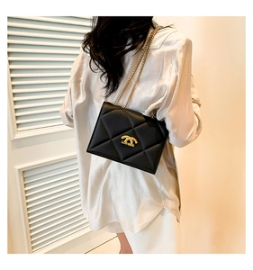 Detail of black quilted leather shoulder bag with gold chain strap and metal logo