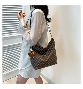 Lifestyle view of brown vintage bucket bag with monogram pattern and plush charm