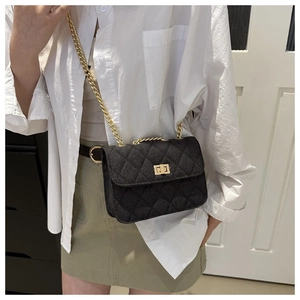 Detail view of a black quilted crossbody bag with gold chain strap and square turn-lock