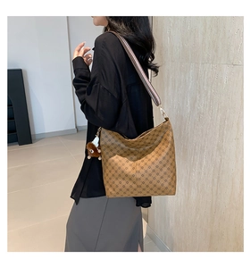 Brown tote bag with diamond pattern and striped shoulder strap shown on a model