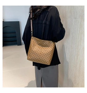 Detail of retro bucket bag with vintage monogram pattern and wide woven shoulder strap