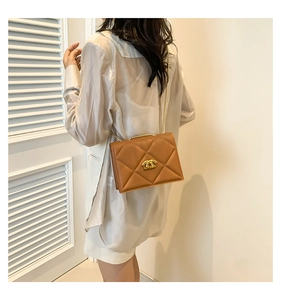 Detail of a brown quilted leather crossbody bag with gold chain and interlocking lock