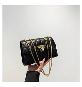 Detail view of black quilted leather shoulder bag with gold chain and metal lock