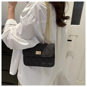 Sac bandoulière en denim noir matelassé avec chaîne dorée porté par un mannequin