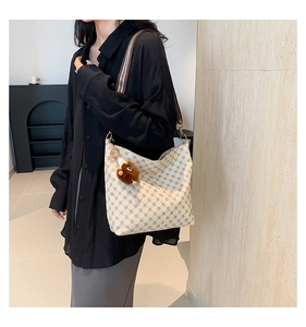 Detail view of large bucket bag with geometric pattern and cute bear plush charm