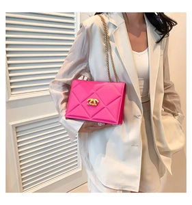 Detail of bright pink quilted crossbody bag with gold chain and metal logo