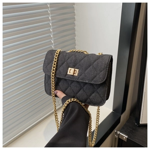 Détail du sac matelassé en denim noir avec fermoir doré et bandoulière en chaîne