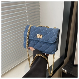 Détail du sac bandoulière en denim bleu avec motif matelassé et chaîne dorée