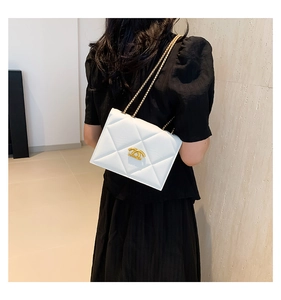 Detail of white quilted chain bag with gold logo on model back for styling perspective