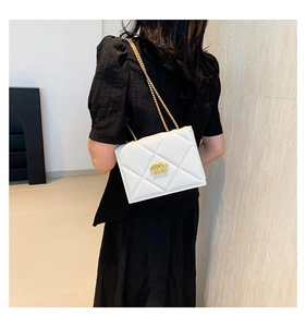 Close-up of white quilted leather chain bag with gold logo on black dress model