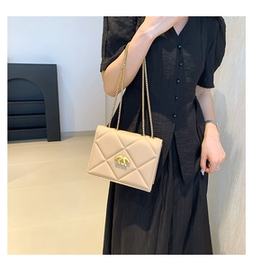 Detailed view of beige quilted leather crossbody bag with elegant gold chain strap