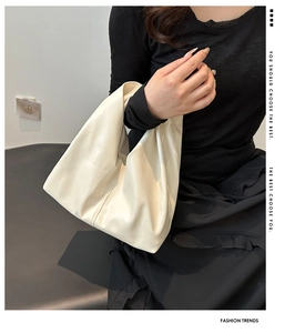 Detailed view of cream-colored slouchy tote bag with soft leather texture on shoulder