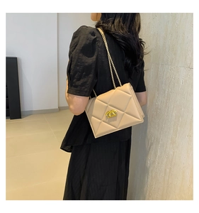 Detail shot of beige quilted flap bag with gold chain strap worn by model