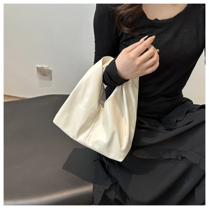 Detail view of a minimalist cream PU leather hobo bag with a soft texture and single handle
