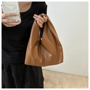Detailed side view of a brown pleated PU leather handbag with a minimalist handle