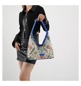 Détail de la broderie florale sur tote bag en toile beige avec finitions en cuir bleu