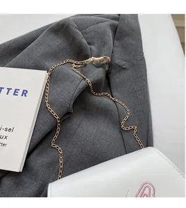 Détails du sac selle en cuir blanc avec broderie rose et bandoulière en chaîne dorée