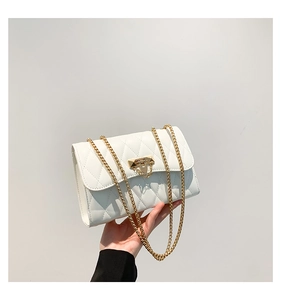 Close-up of white quilted crossbody bag with gold chain strap and metal clasp detail