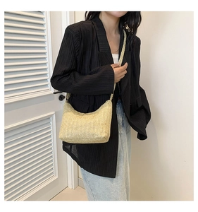 Vue détaillée d'un sac hobo en paille tressée beige porté avec une tenue d'été décontractée