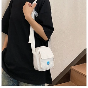 Detailed view of the white canvas messenger bag with blue geometric logo embroidery