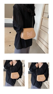 Gros plan sur un sac besace kaki avec broderie papillon et bandoulière en chaîne dorée