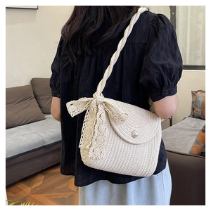 Close-up of beige woven bucket bag featuring a lace bow and elegant pearl buckle detail