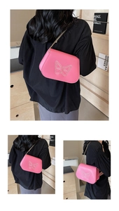 Détail du sac selle rose avec broderie papillon et bandoulière en chaîne dorée