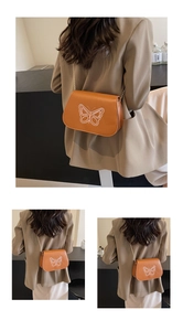 Détail d'un sac bandoulière orange avec broderie papillon et fine chaîne dorée