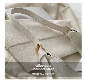 Détail de la bandoulière réglable avec boucle en métal doré sur le sac blanc texturé
