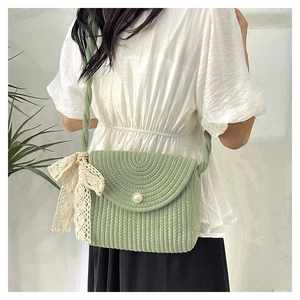 Detail of light green woven crossbody bag with pearl buckle and lace ribbon bow