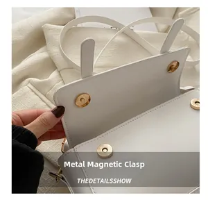 Detail of the white leather bag featuring secure double gold magnetic hardware snaps