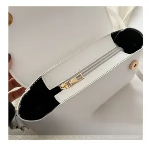 Detail view of smooth metal zipper and magnetic closure on white leather handbag