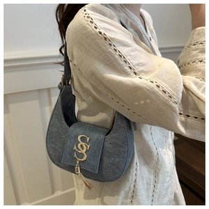 Vue détaillée du sac porté épaule bleu denim avec logo S doré et pompon à franges