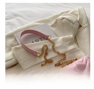 Detail of pink quilted shoulder bag featuring gold chain strap and leather stitching