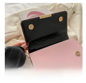 Detailed view of pink leather handbag with gold metal magnetic snap closure and black flap