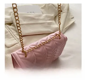 Detail view of pink quilted shoulder bag with golden metal chain and envelope side structure