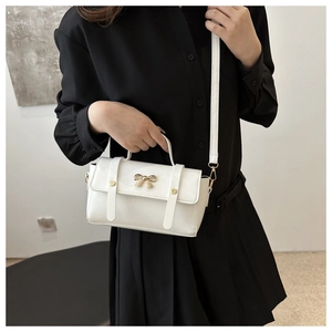 Elegant white leather crossbody bag with a golden bow buckle and dual straps for women