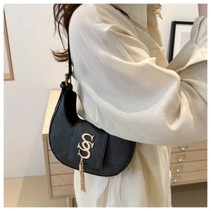 Détail du sac croissant noir avec logo doré et pendentif à pampilles en chaîne