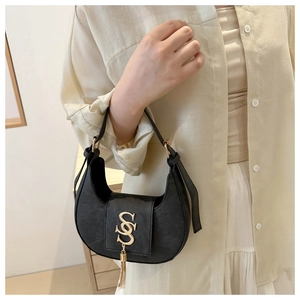 Gros plan du sac hobo noir avec logo S doré et détails de pompons métalliques chic