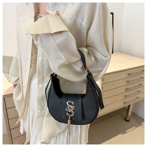 Détail du sac hobo noir avec logo doré et pendentif à franges métalliques longues