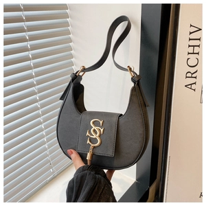 Détail du sac demi-lune noir avec fermoir doré à double S et décoration de pompons