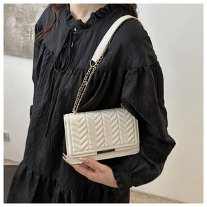 Elegant cream quilted crossbody bag with gold chain strap shown on black dress