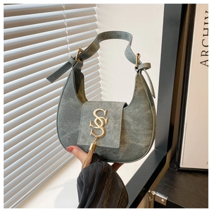Détail du sac hobo en jean bleu avec boucle logo dorée et accessoire à pompon