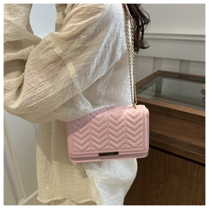 Detail of pink chevron quilted crossbody bag with golden chain and metallic buckle