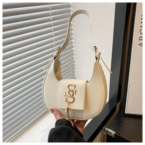 Détail du sac croissant crème avec logo S doré et gland métallique élégant en gros plan