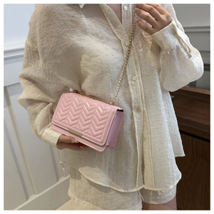 Close-up of pink chevron quilted leather surface with elegant gold metal chain and strap