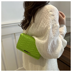 Detail view of bright green V-quilted small square bag with elegant gold chain strap