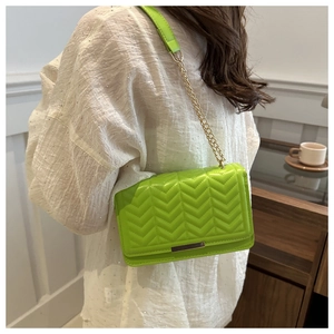 Detail of neon green crossbody bag with V-shaped quilting and gold metal chain strap