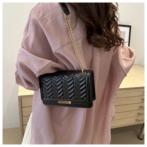 Detail of black V-quilted faux leather crossbody bag with elegant gold chain and buckle