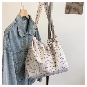 Détail du sac cabas crème à motif floral violet avec cordon de serrage et bandoulière